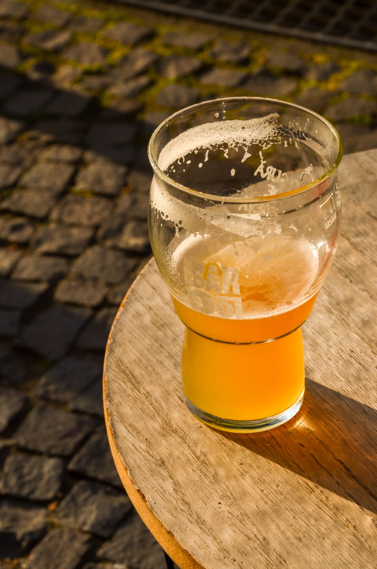 Ein selbstgebrautes Pale Ale steht auf einem Holztisch während die Sonne in das bier scheint.
